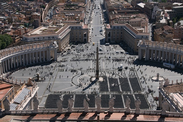 La celeberrima piazza San Pietro, notevole esempio di architettura ed urbanistica barocca, è dedicata all'omonimo santo ed è quotidiano punto d'incontro per migliaia di fedeli cattolici provenienti da tutto il mondo. La piazza ha una forma ad ovato tondo, l'unione di due semicirconferenze che si intersecano nei rispettivi centri unite da due archi di cerchio. L'idea dell'ovato tondo, del Bernini, in forte contrapposizione alla basilica longitudinale, serviva a reggere la spinta della sequenza formata dalla chiesa e dal suo sagrato. L'Obelisco Vaticano, che si innalza al centro della piazza, è di origine egiziana e proviene dalla città di Heliopolis; prima venne sistemato ad Alessandria d'Egitto e in seguito fu portato a Roma da Caligola nel 40, e collocato sulla spina del Circo di Nerone. Rimase in questa posizione anche dopo che il circo cadde in disuso, occupato da una necropoli. Si ritrovò poi a fianco dell'antica basilica di San Pietro, presso la Rotonda di Sant'Andrea. Fu dunque spostato e rialzato per volere di papa Sisto V nel 1586. Secondo una leggenda, quando il 10 settembre 1586, l'obelisco fu issato sul basamento attuale in Piazza San Pietro, le corde che lo sostenevano minacciarono di rompersi. Dalla folla accorsa a vedere l'evento, si levò un grido: "Acqua alle corde!". Era il suggerimento di un capitano sanremese, un certo Bresca, che conosceva il comportamento delle corde a contatto con l'acqua. La tradizione vuole che grazie al suo consiglio si riuscì a portare a termine l'operazione ed egli fu premiato da Sisto V con una grazia: il privilegio, per sè, per la sua famiglia e per i suoi discendenti, di fornire al Vaticano le palme per la cerimonia della domenica delle Palme. Privilegio mantenuto ancora oggi.  Piaciuta questa curiosità? Se vuoi leggerne altre, su migliaia di città, scarica Secret Maps!